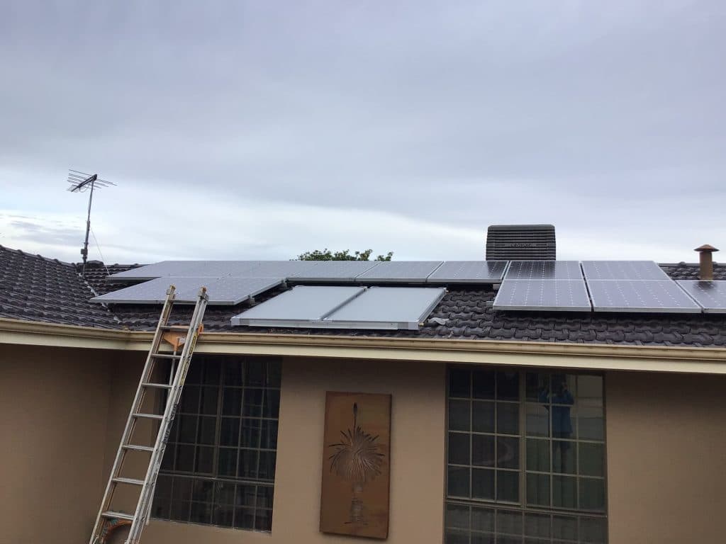 Solar Hot Water 14 Solar power system installation on a home roof. Renewable energy with solar panels and a ladder for access.